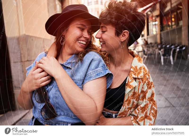 Merry girlfriends hugging on narrow street women couple smile happy together lesbian weekend madrid spain female young summer glee lgbt close cheerful embrace