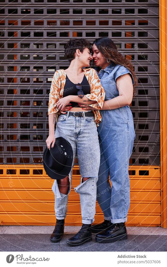 Loving girlfriends embracing on street women couple hug love smile wall touch nose happy lesbian madrid spain female young together date affection optimist glad