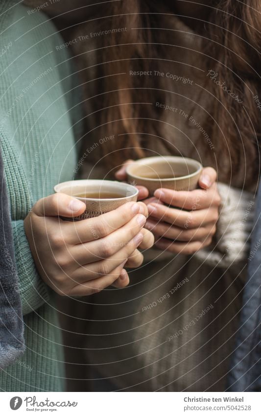 https://www.photocase.com/photos/5042528-detail-shot-of-two-young-women-in-cozy-sweaters-with-tea-cups-in-hands-photocase-stock-photo-large.jpeg