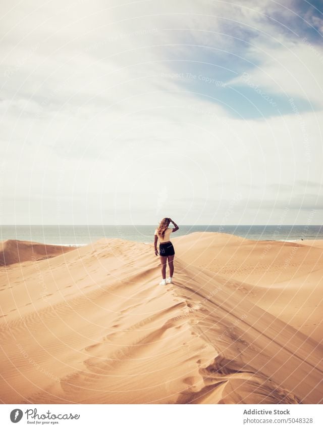 Woman standing on dune and admiring sea woman admire beach tourist explore cloudy blue sky sand maspalomas gran canaria canary islands spain weekend observe