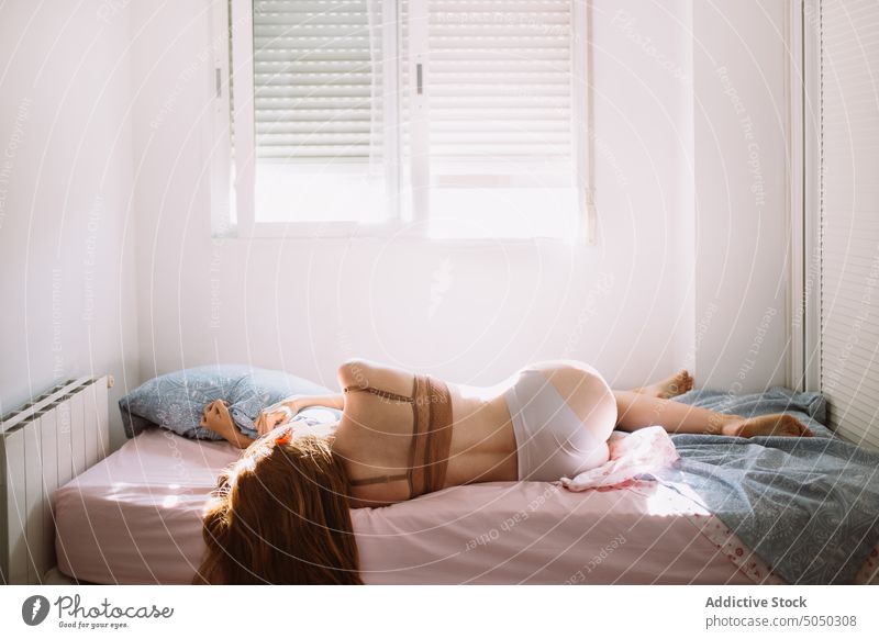 Foto de young pretty woman in black bra sitting on bed. morning time do  Stock