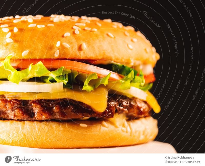 Tasty grilled beef burger with patty, onion, vegetables, melted cheese, lettuce and mayonnaise sauce. American fastfood, unhealthy fat junk yummy food concept