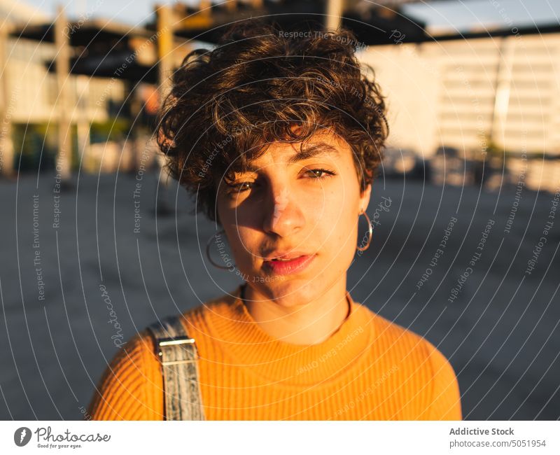 Pensive woman standing on sunny street thoughtful pensive calm sunlight casual shadow city urban personality female alone short hair serious individuality