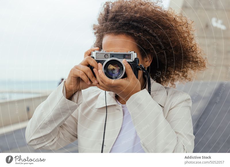 Black woman with photo camera tourist vacation road style curly hair female journey travel lady trendy summer carefree daytime afro pleasure casual young outfit