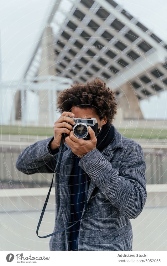 Black man with photo camera tourist vacation road style afro hair journey travel trendy summer carefree daytime pleasure casual young outfit tourism confident