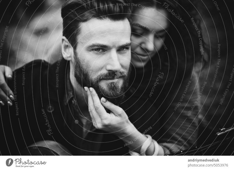 black and white photo of caucasian couple in love in autumn nature. Young bearded man and curly woman are hugging on the shore of a lake. young lovers freedom