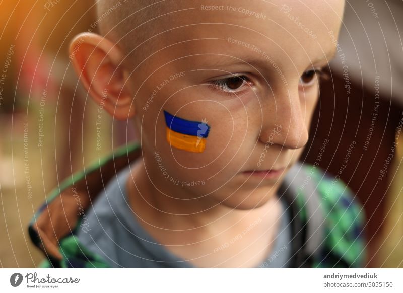 close up of smiling child with painted Ukrainian flag on face. Protest against Russian war invasion in Ukraine. Ukrainian Flag, Protesters concept conflict
