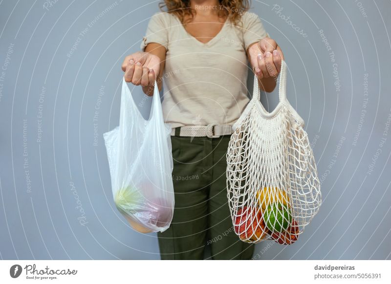 Unrecognizable woman comparing reusable mesh bag and disposable plastic bag with fruits unrecognizable faceless female holding comparison reusable bag