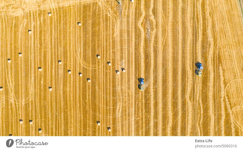 Aerial view of tractors as tow trailed bale machines to collect straw from harvested field Above Agricultural Agriculture Bale Baler Baling Cereal Collect