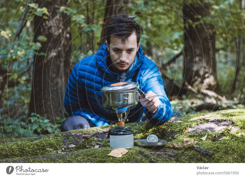 https://www.photocase.com/photos/5061950-man-in-a-blue-down-jacket-boils-water-for-tea-and-food-on-a-portable-stove-and-in-a-stainless-steel-ultralight-pot-in-the-middle-of-the-wilderness-hiking-lifestyle-photocase-stock-photo-large.jpeg