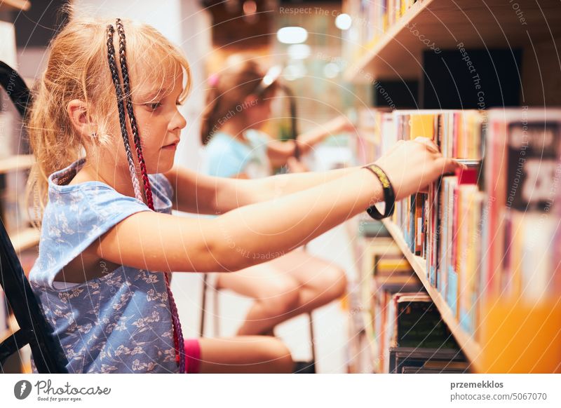 Schoolgirls looking for books in school library. Students choosing books. Elementary education. Doing homework. Back to school back schoolgirl child reading