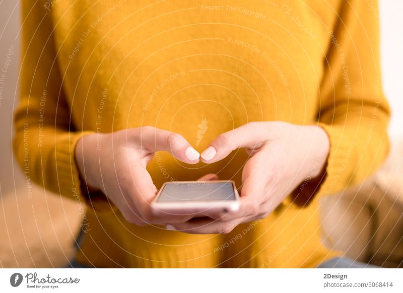 Closeup of woman's hand in yellow pullover, using smartphone person technology typing communication female closeup lifestyle mobile business adult mobile phone
