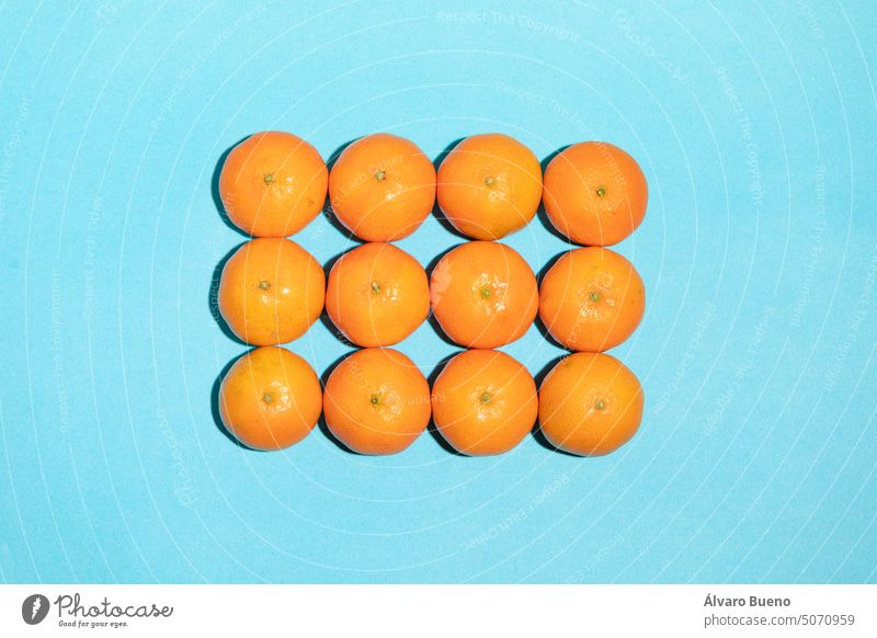 Juicy and natural arranged tangerines forming a rectangle mandarins fruits vitamin c background blue texture rows columns shape irregular concept imperfection