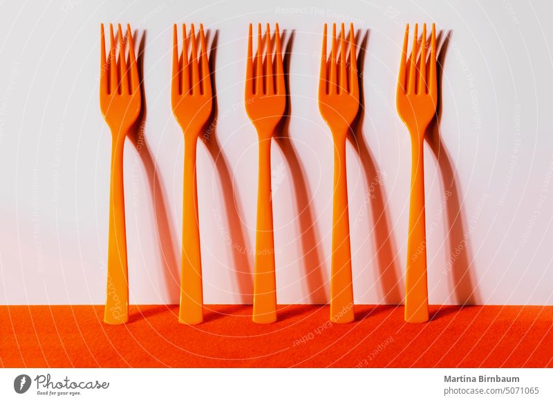 Orange plastic forks in a row yellow object equipment background colorful macro dining abstract close composition flat lay accessories design vivid disposable
