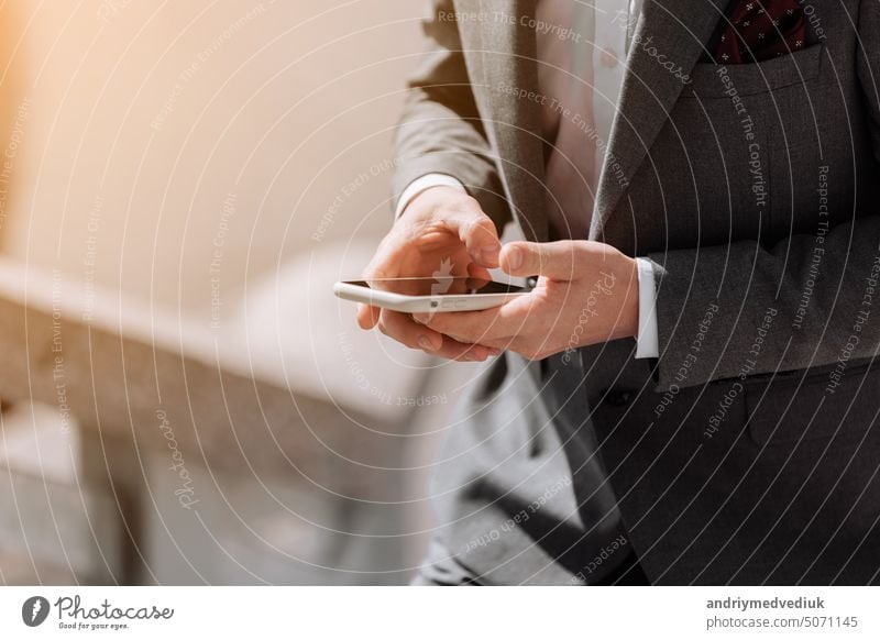 Closeup shot of an unrecognisable businessman in suit is using smartphone outdoors by the office. Making moves in the corporate world. Staying on top of the latest business news. copy space