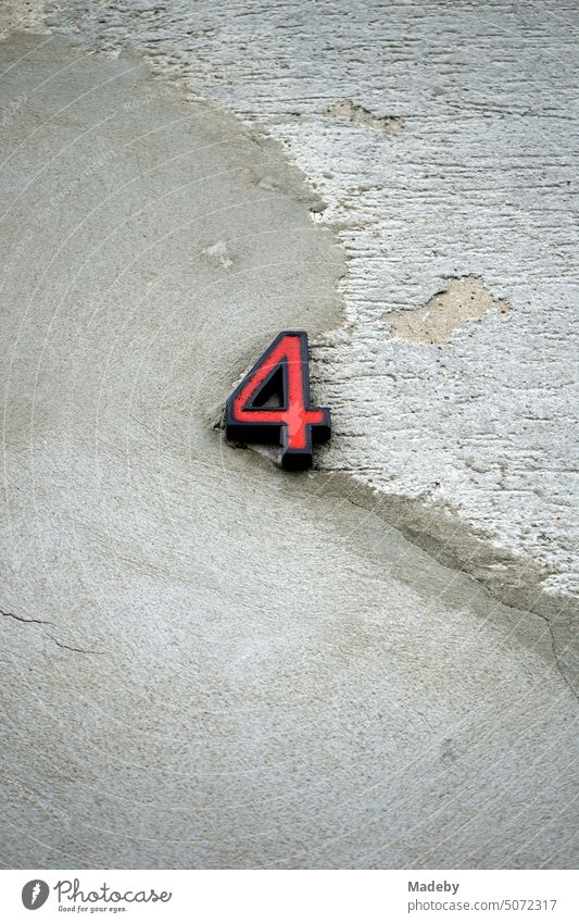 Red house number four on old masonry with crumbling plaster in natural colors of the facade of a residential building in Oerlinghausen near Bielefeld on the Hermannsweg in the Teutoburg Forest in East Westphalia Lippe