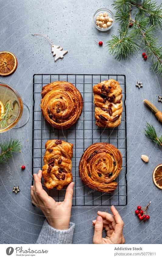 Person grabbing baked pastry from Christmas table food plait sweet roll hand plate christmas decoration homemade pine tree tradition arrangement dessert