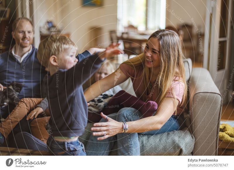 Happy young family having good time together at home real life real people bonding indoors quality time house parenting kids enjoyment fun happy togetherness