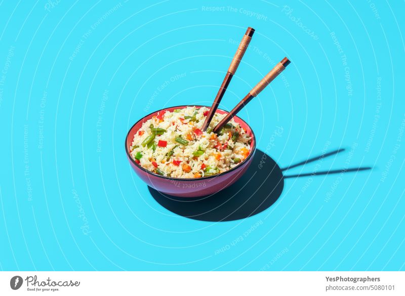 Fried rice bowl isolated on a blue background asian beans bright carrot chinese chopsticks color cooking copy space cuisine cut out delicious design diet dinner