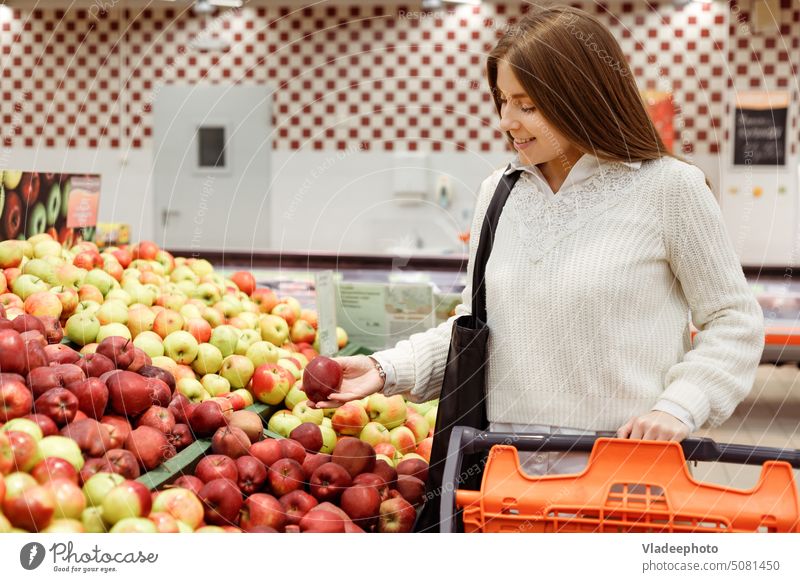 Woman buys fruits and vegetables at a market, apple supermarket store customer food basket cart consumer grocery people retail shopper choice healthy woman