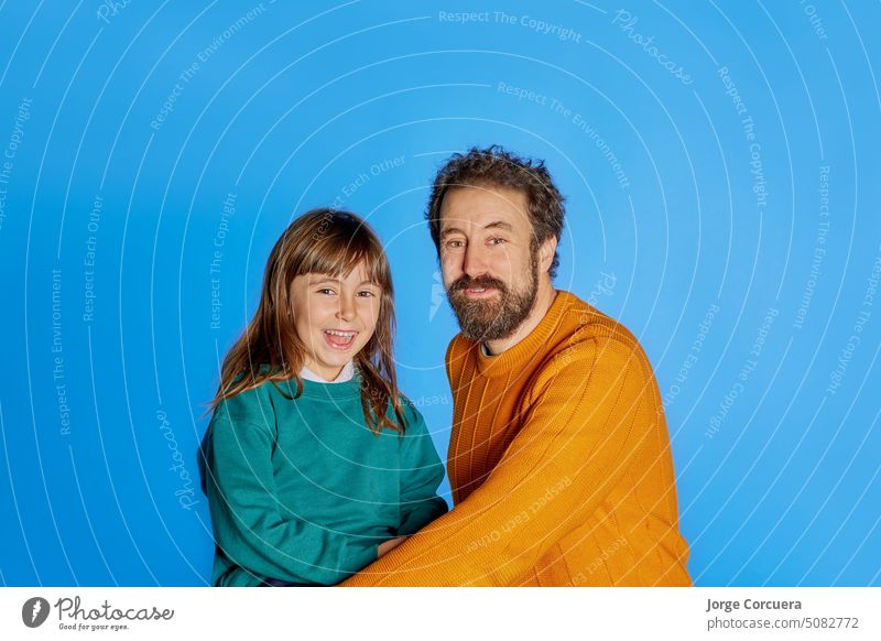 Family portrait father and 6 year old daughter. showing happiness on isolated blue studio background. Father day parenthood childhood concept family dad funny