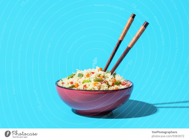 Bowl with fried rice and vegetables minimalist on a blue background asian beans bowl bright carrot chinese chopsticks close-up color cooking copy space cuisine