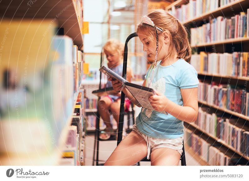 Schoolgirls looking for audio books in school library. Students choosing books. Elementary education. Doing homework. Back to school back schoolgirl child