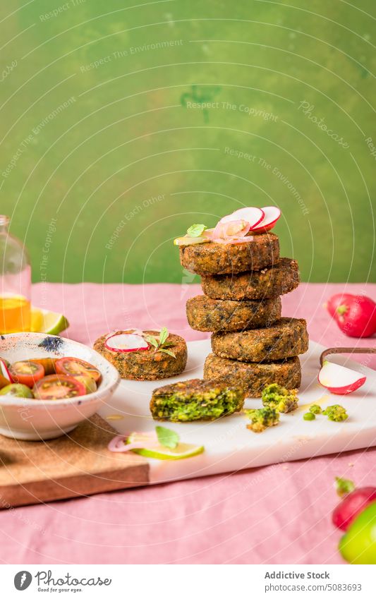 Vegetarian fritters served on cutting board near bowl of cherry tomatoes squeeze lime stack vegetarian fresh colorful bright juice add vegan vegetable feast