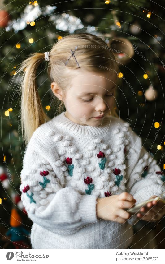 Toddler girl with pigtails playing with ornaments from a christmas tree Santa Claus background blonde bright celebration child childhood cute december