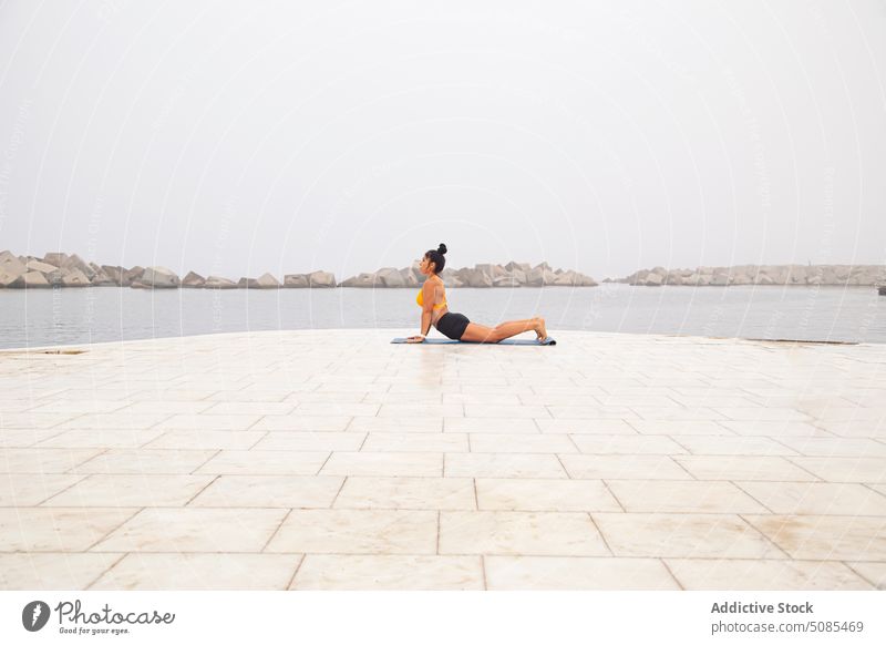 Sportive woman doing Cobra pose on mat near sea with stones - a Royalty  Free Stock Photo from Photocase