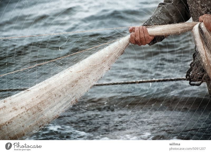In stormy sea the fisherman hauls in the net fishing Fishing net Hand Fisherman Fishery Net Catch Network Work and employment Ocean Baltic Sea Lake Water