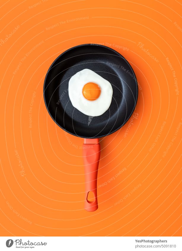 Fried egg in a cooking pan, top view on an orange background above breakfast bright color concept copy space creative cuisine cut out delicious design diet