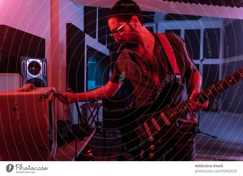 Man using amplifier while playing electric guitar man adjust music studio guitarist musician illuminate male modern sound hobby instrument equipment entertain