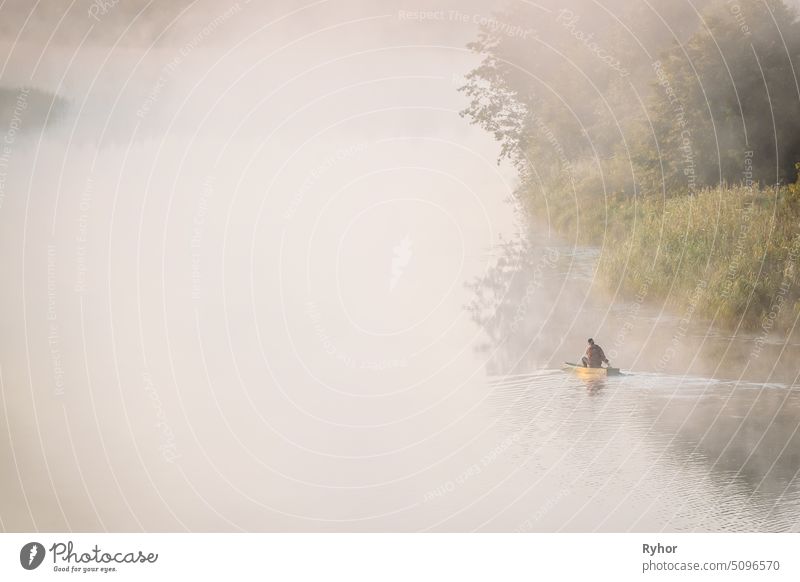Calm Lake, River And Man Fishing From Old Wooden Rowing Fishing Boat At Beautiful Misty Sunrise In Summer Morning. Fisherman Is In Wooden Boat. Russian Nature. Ecotourism