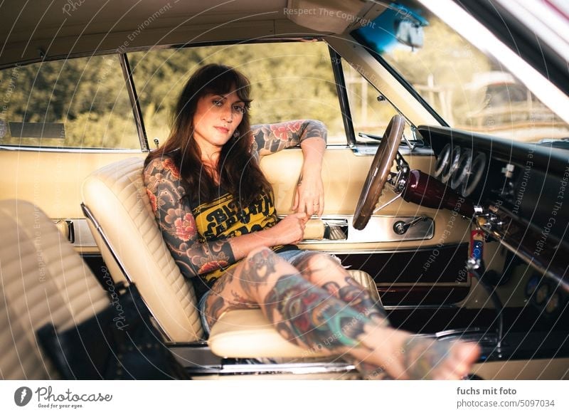 Person with tattoos in car. Vintage car. Woman in old car Steering wheel Tattoo Cool pretty Lifestyle youthful Modern portrait Summer Car Tattooed Fashion