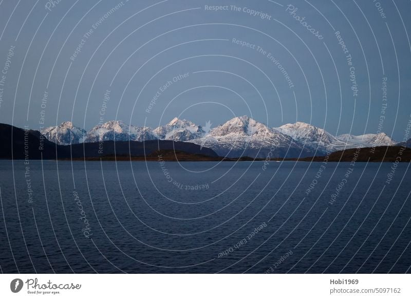 Snow covered mountains on the coast near Alta in Norway snow-covered Ocean ocean Sea water Cold chill Frost White sky Horizon Fjord salt water panorama Nature