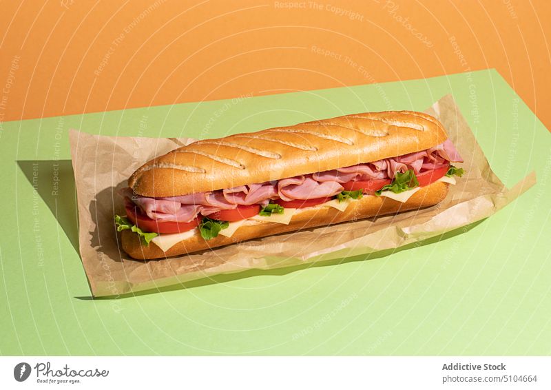 Sandwich with ham and fresh lettuce sandwich breakfast baguette meat food snack cheese tomatoes green background baking paper overlay copy space sub sandwiches