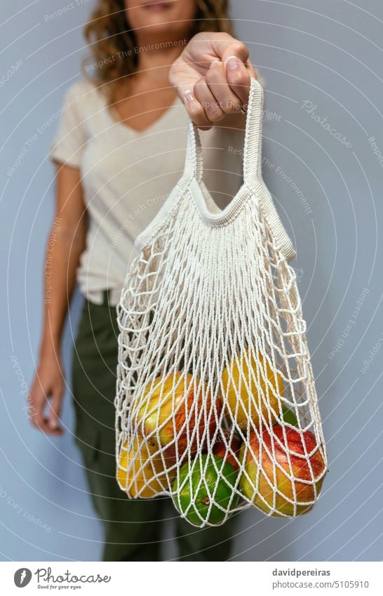 Unrecognizable woman holding reusable mesh bag with fruits inside unrecognizable faceless female showing reusable bag string bag eco bag zero waste eco friendly