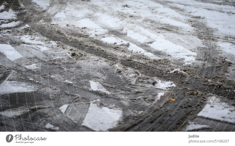 Traces of car tires in the snow on asphalt abstract auto backgrounds black blizzard close-up cold concepts condition contrast curve direction frost frozen