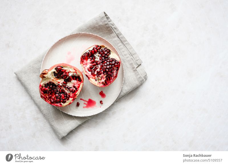 Halved pomegranate with seeds on a plate. View from above. Pomegranate Plate halved fruit Fruit Red Juicy Mature Healthy Nutrition Delicious cute Food