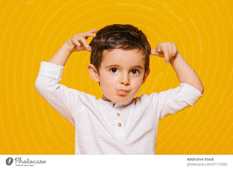 Cute boy touching hair and looking at camera and looking at camera kid child girl cute gesture casual little amazed adorable childhood happy joy bright