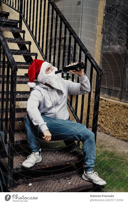 Homeless Santa drinking wine and rummaging through garbage bins alcohol alcoholic bad santa beard begging bottle brutal caucasian celebration charity christmas