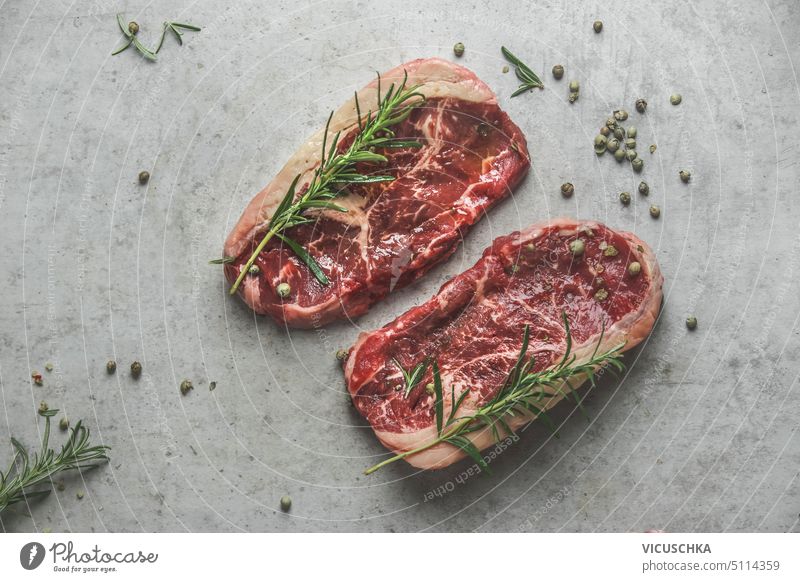 Raw marble black angus steak with rosemary and green pepper on grey concrete kitchen table. Top view. raw top view fillet meat background beef butcher