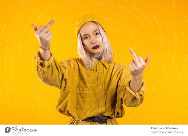 Young rude woman on yellow background showing middle finger - gesture of fuck. person young aggression female adult hand sign beautiful anger aggressive bad