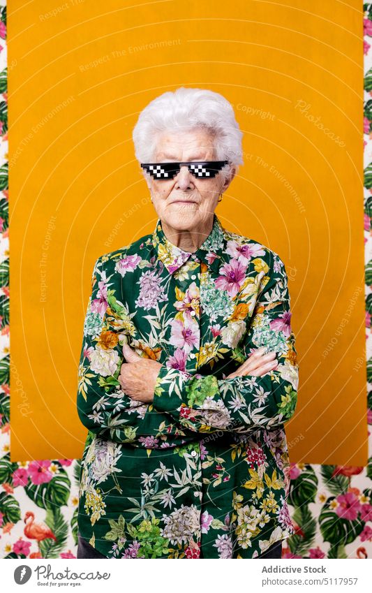 Confident elderly female in pixel sunglasses woman confident style arms crossed appearance floral ornament colorful bright portrait senior aged pensioner retire