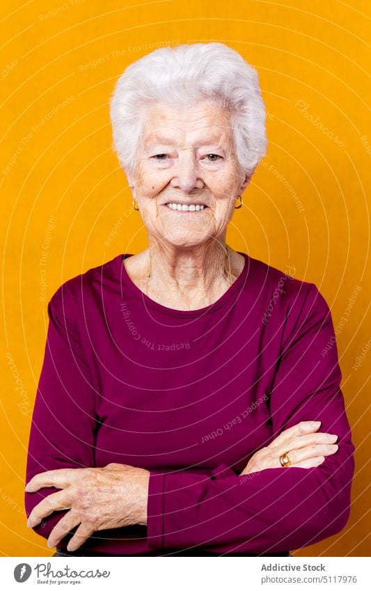 Positive senior woman with crossed arms smile casual happy pensioner style gray hair appearance colorful bright female elderly aged retire glad cheerful wrinkle
