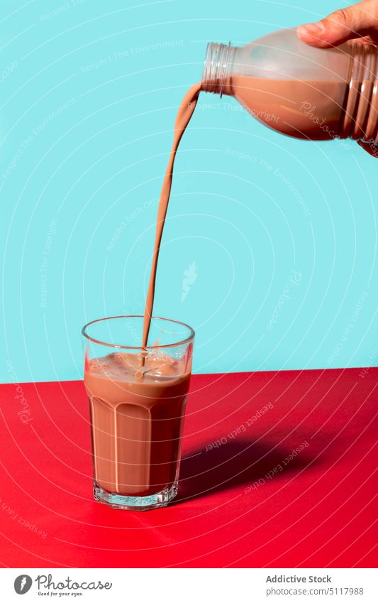 Crop person filling glass with chocolate drink pour milk bottle sweet tasty colorful bright plastic beverage yummy delicious liquid fresh cocoa milkshake flavor