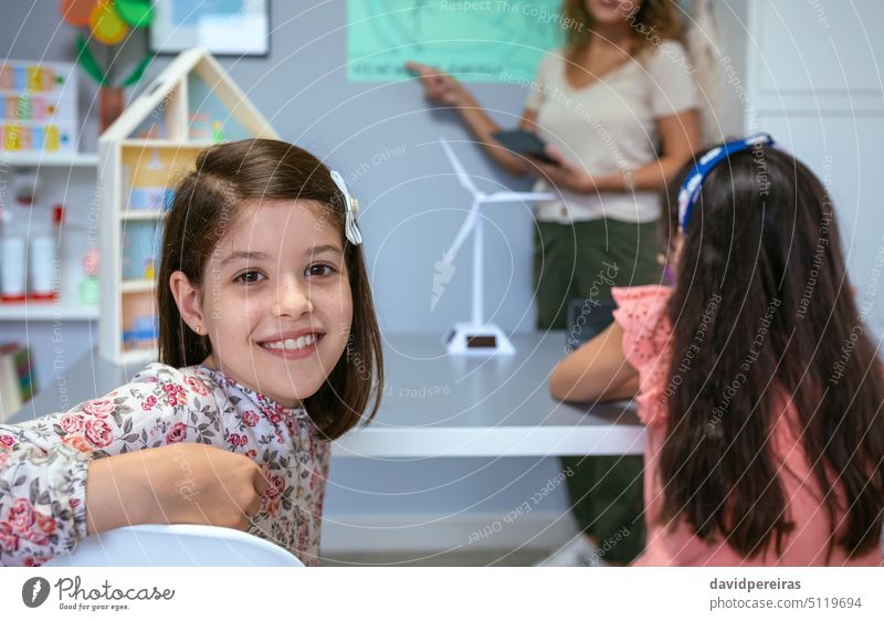 Portrait of schoolgirl in ecology classroom and teacher explaining lesson on background female student portrait looking at camera smile renewable energy happy