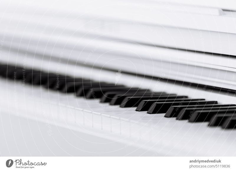 Close side view of shiny black and white piano keys with the reflection of the white edge from low angle with shallow depth of field. selective focus keyboard