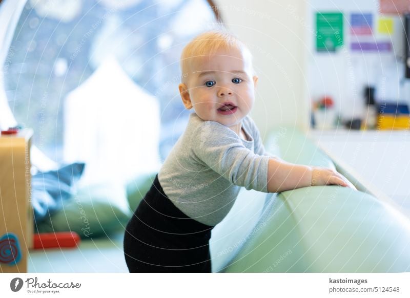 Little infant baby boy trying to stand while playing in kindergarten little kid childhood happy adorable toddler cute young small portrait people happiness joy